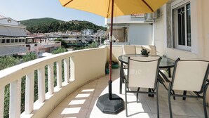A balcony with a yellow umbrella, a table, and two chairs.
