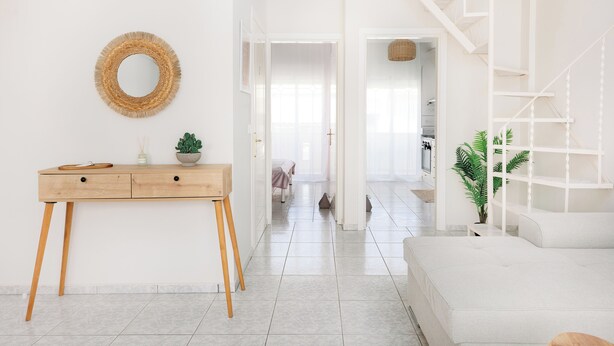 A bright, spacious room with a wooden desk, a white sofa, and a staircase.