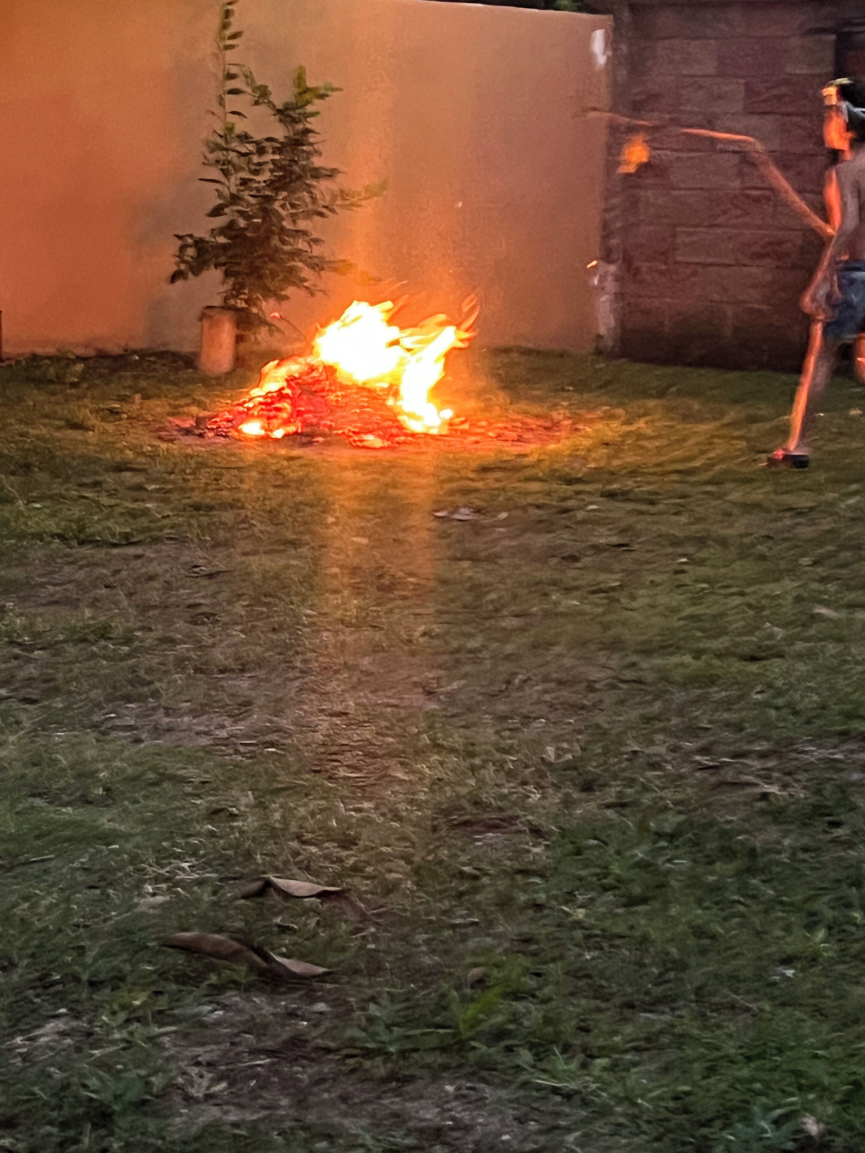 A fire burning on the ground with a person standing nearby.
