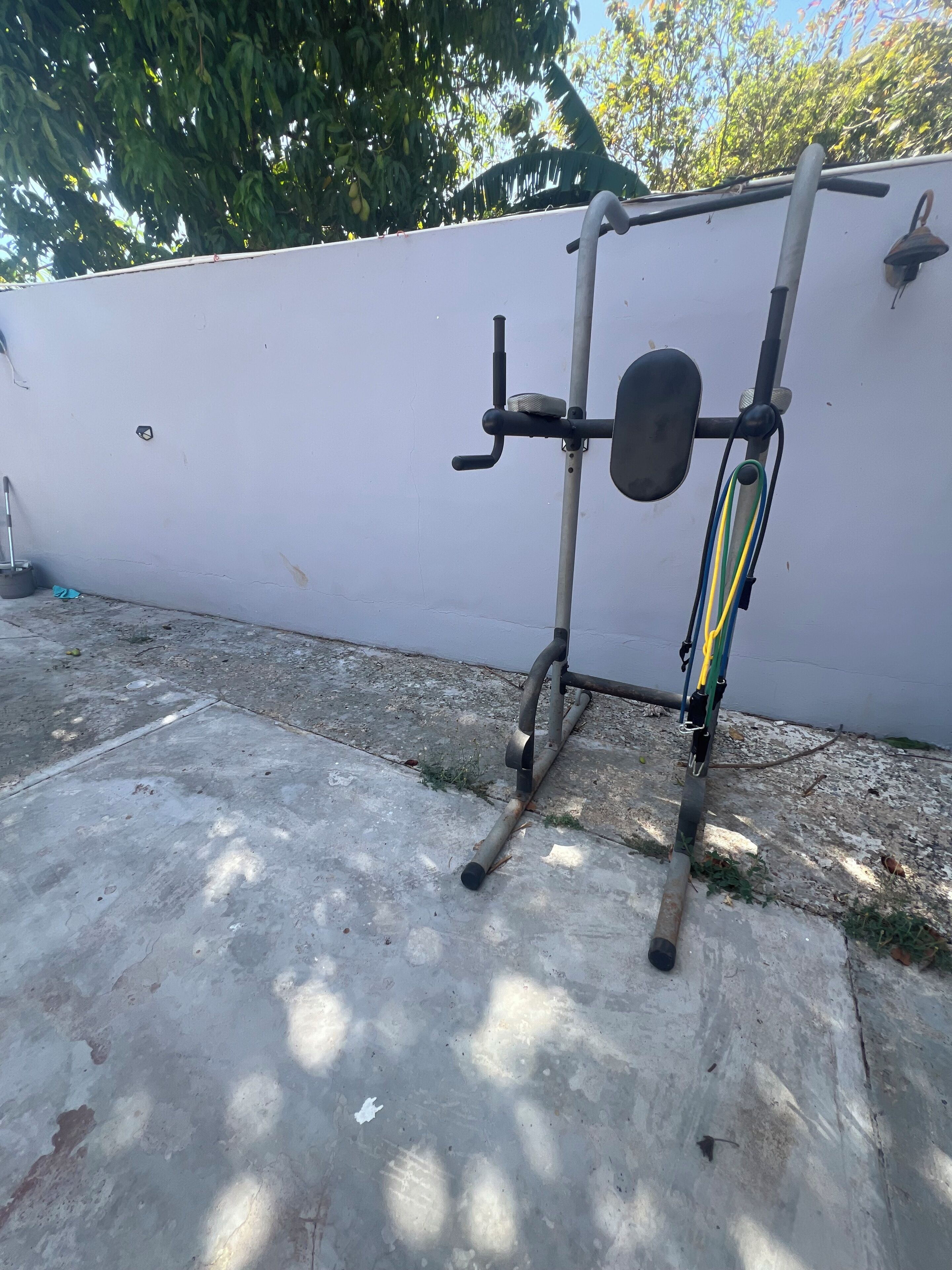 A concrete floor with a white wall and a metal exercise bar.