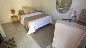 A bedroom with a bed, a chair, a mirror, and an air conditioning unit. - olivias village room (Capellania)