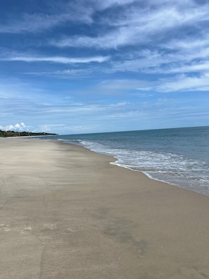 A beach with a wide sandy shore and gentle waves.