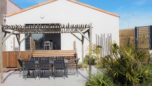 Une maison dotée d’un patio couvert, d’un espace salon extérieur et d’un jardin.