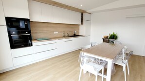 Une cuisine moderne avec des armoires blanches, un plan de travail en bois et un four encastré.