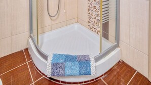 A glass-enclosed shower area with a handheld showerhead and a handheld showerhead with a rain shower attachment. - NIKOLA APARTMENTS (Lemnos)