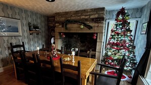 A dining area with a wooden table and chairs, a fireplace, and a decorated Christmas tree. - Beautiful 18th century 10 person Cottage in the heart of NE England w/hotub (Prudhoe)