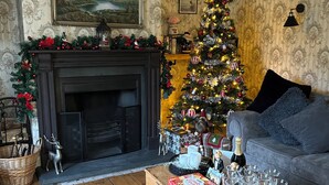 A cozy living room with a fireplace, a Christmas tree, and a sofa. - Beautiful 18th century 10 person Cottage in the heart of NE England w/hotub (Prudhoe)