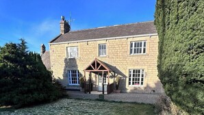 A two-story stone house with a covered porch and a well-maintained lawn. - Beautiful 18th century 10 person Cottage in the heart of NE England w/hotub (Prudhoe)