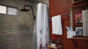 Ein Badezimmer mit Dusche, Handtuchhalter, Toilettenpapierhalter und Waschbecken.