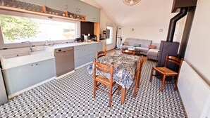 Et kompakt køkken med et vindue, et spisebord med stole og en sofa i en opholdsstue.