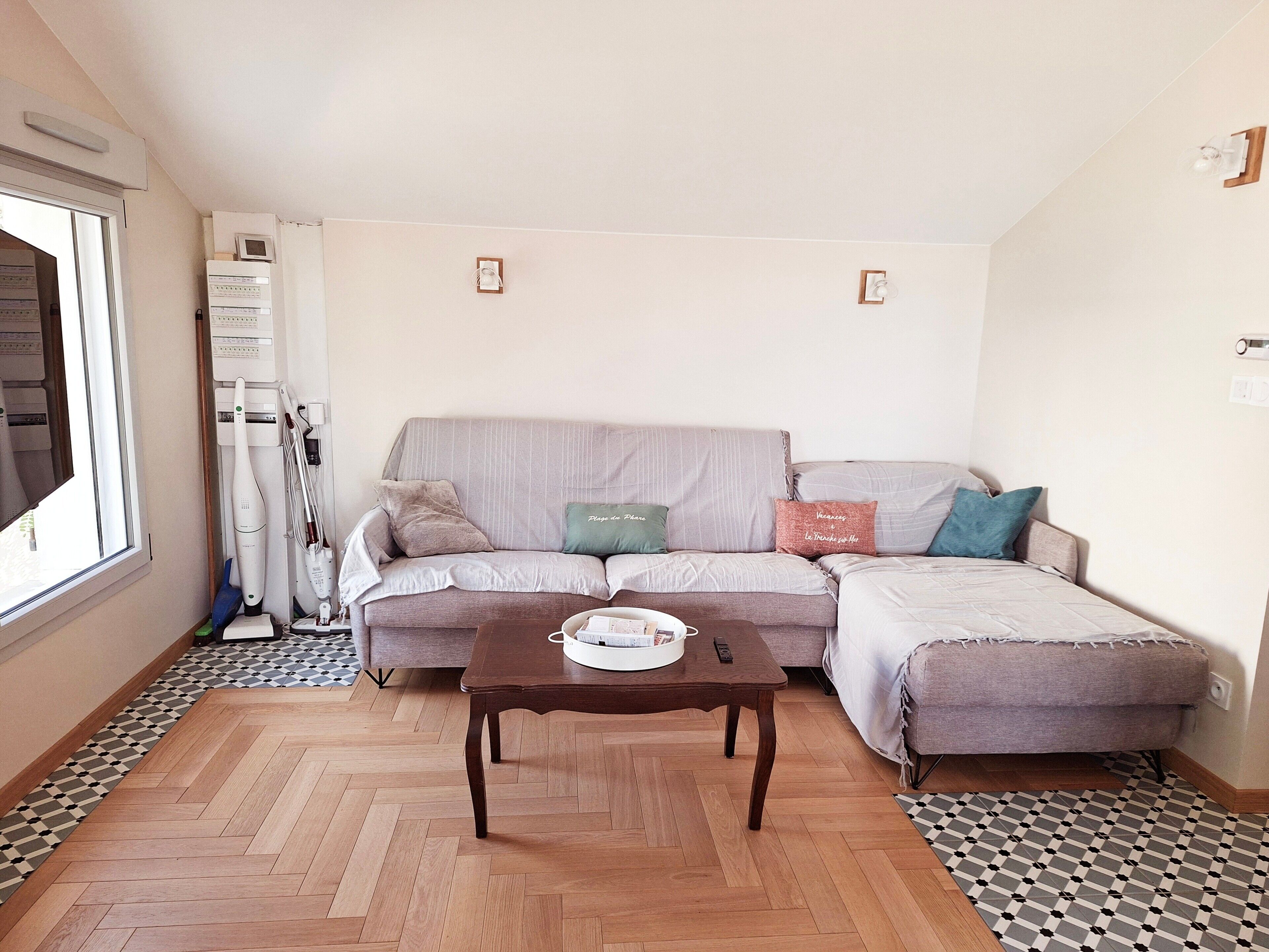 Een woonkamer met een bank, een salontafel en een vloer met een patroon.