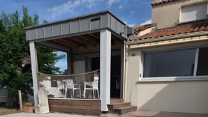 Et moderne hus med en overdækket terrasse, et hvidt stakittence og en postkasse.