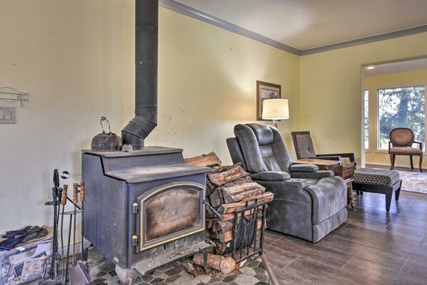 A cozy living room with a wood-burning stove, leather recliner, and a large window.