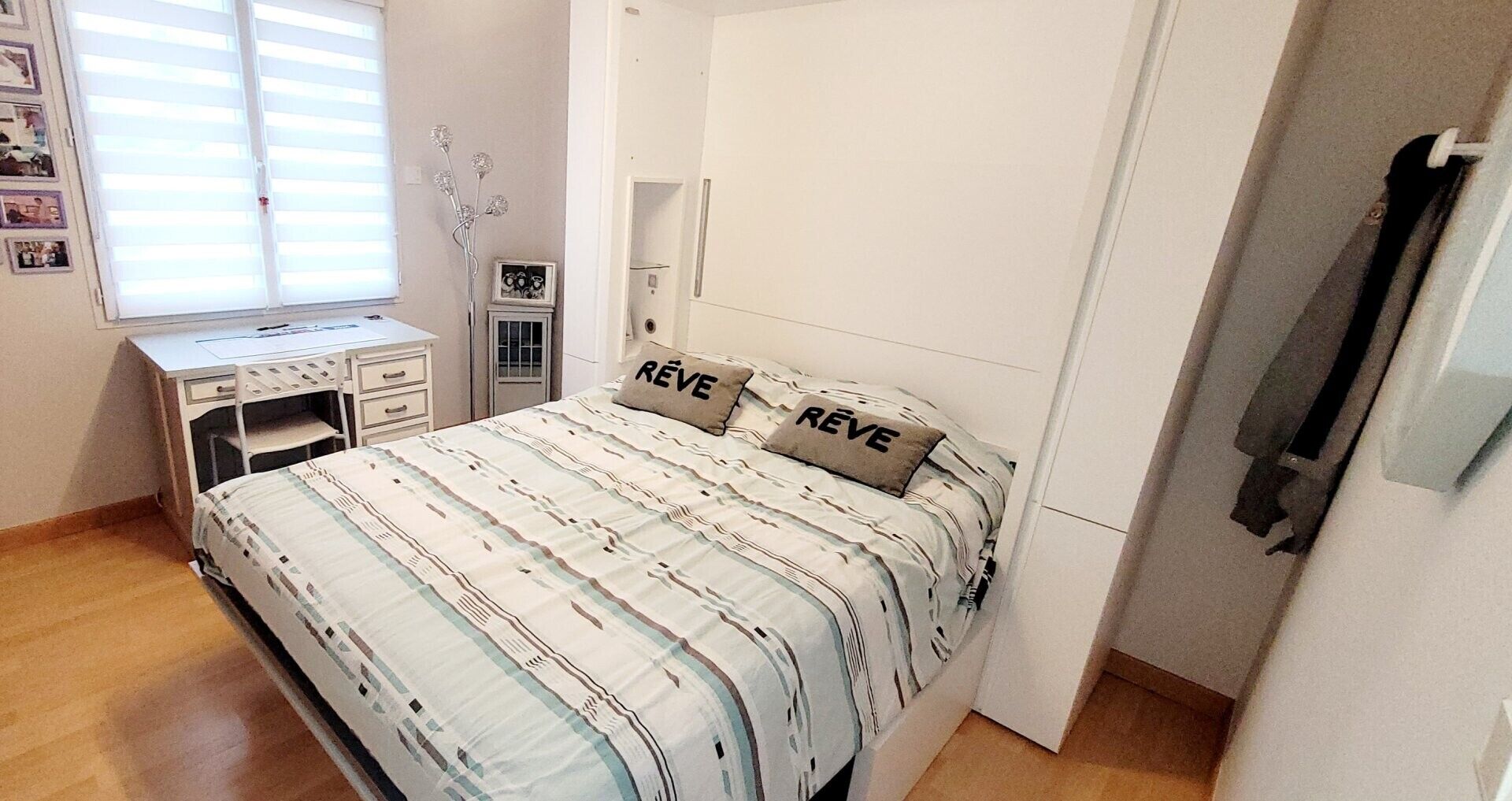 A bedroom with a bed, a desk, and a wardrobe.
