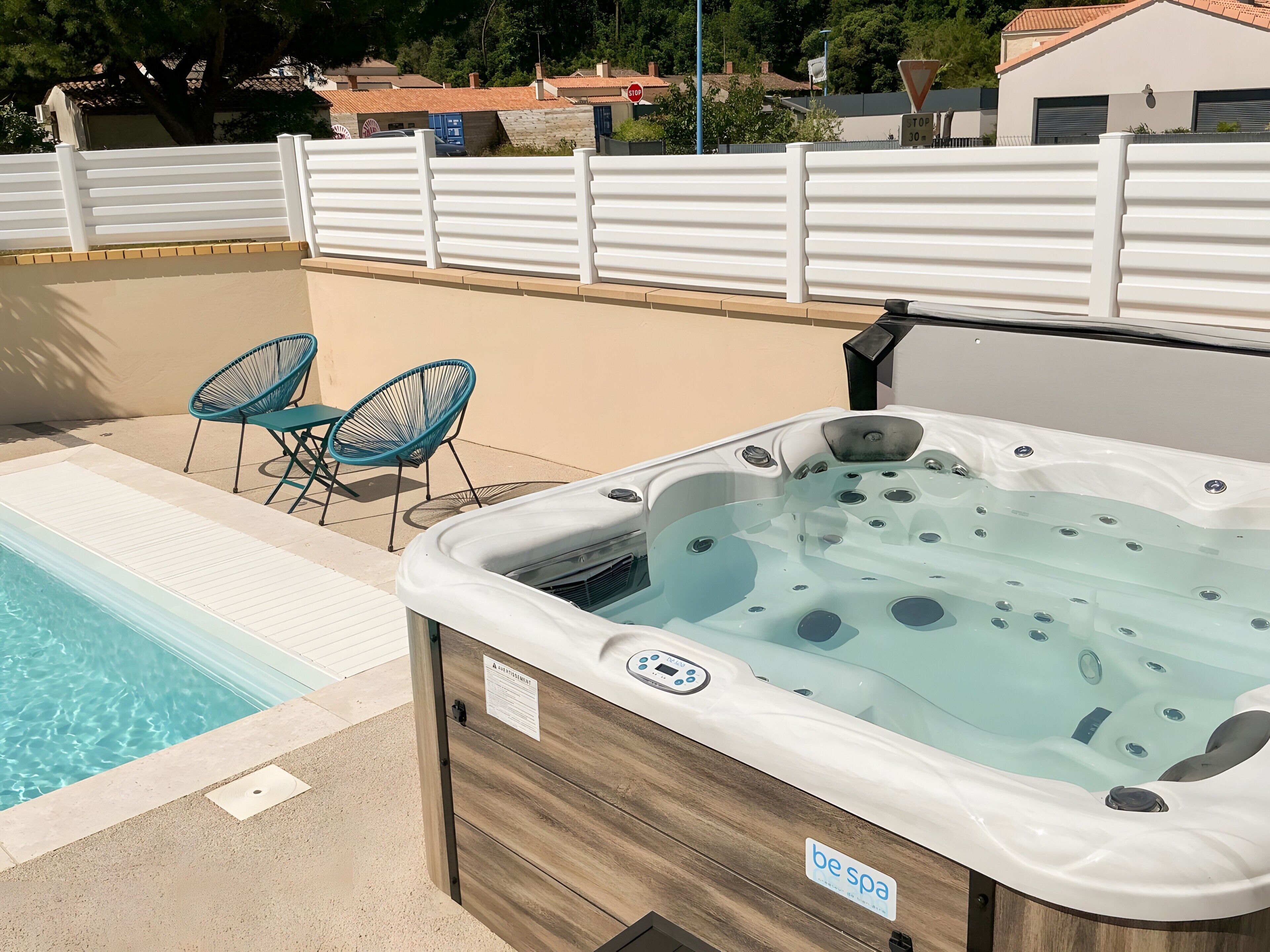 Ein Wellnessbereich mit Whirlpool, Schwimmbecken und zwei blauen Liegestühlen.