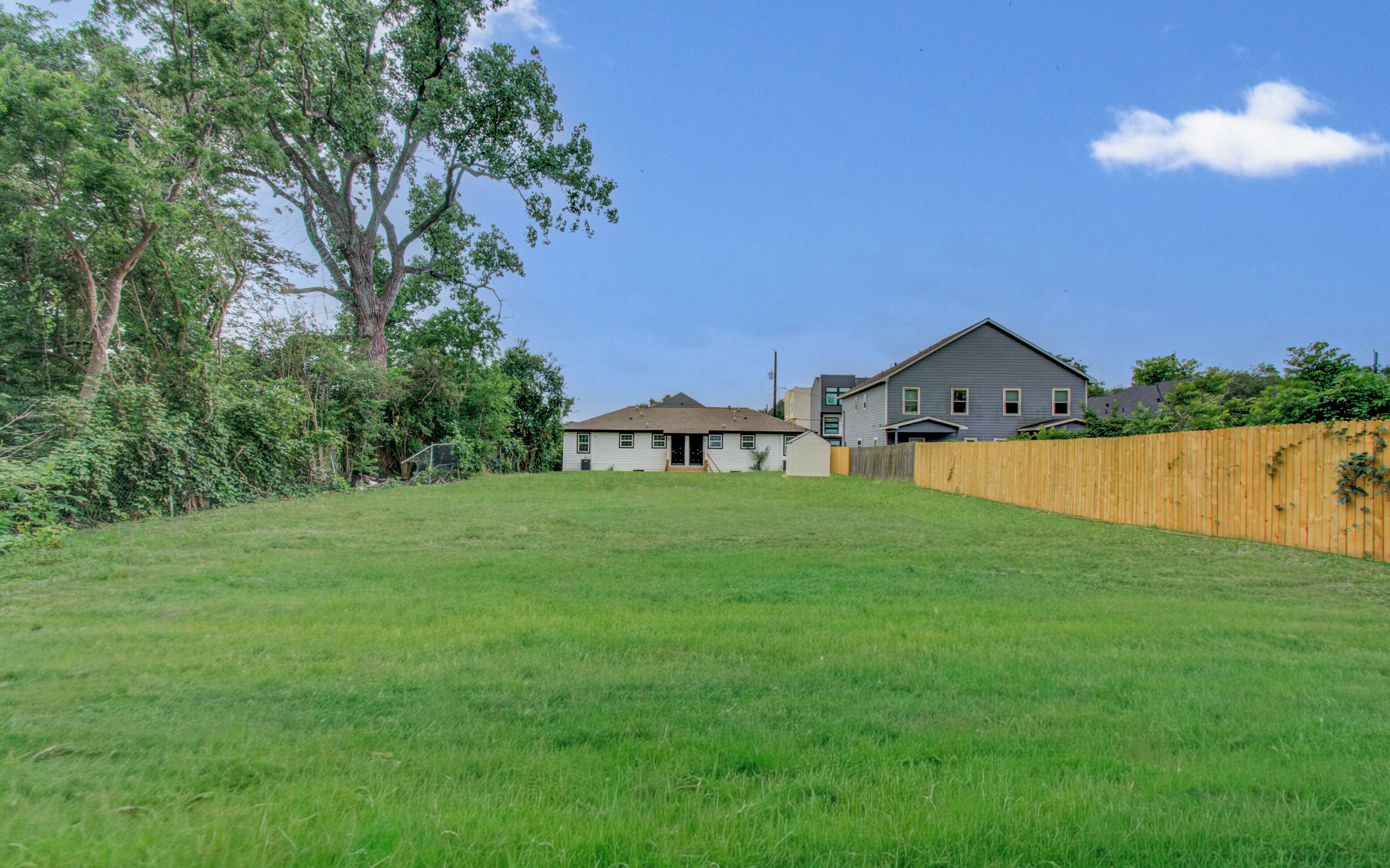 A residential area with a grassy yard, a wooden fence, and houses with a sloped roof.