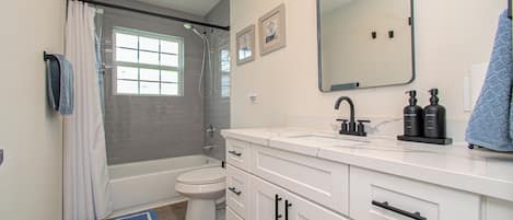 Baño con ducha, inodoro, lavabo y espejo.