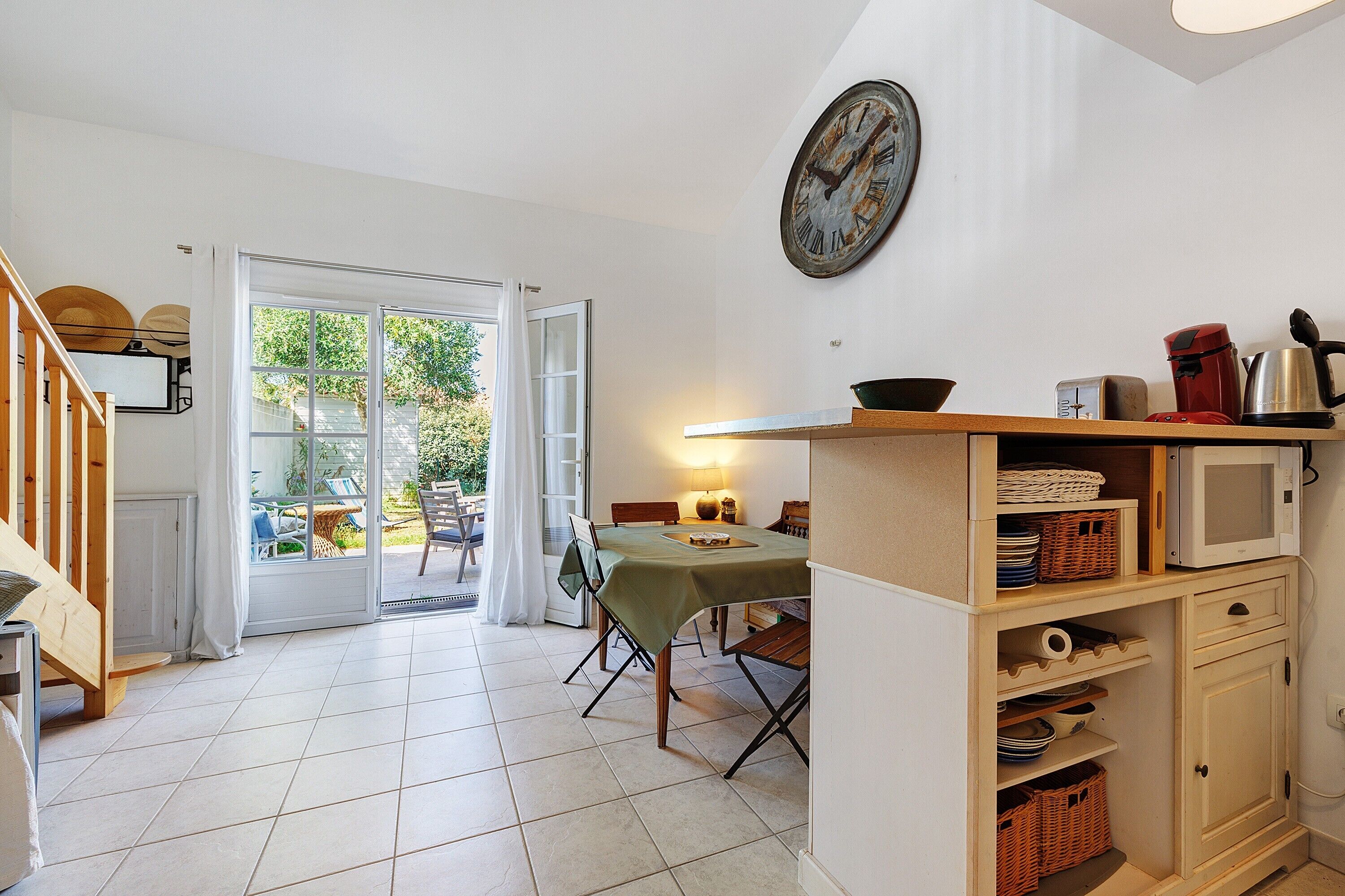 Una cocina con una mesa de comedor, un reloj y vistas al exterior.