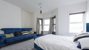 Un dormitorio con una cama, un sofá azul y una ventana.