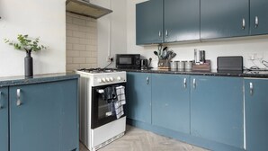 Una cocina con gabinetes azules, una estufa blanca y un microondas.