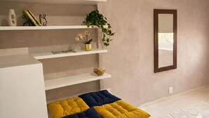 A modern room with white shelving, a mirror, and a bed with yellow and blue bedding. - Apartment just minutes from Copacabana Beach. (Rio de Janeiro)
