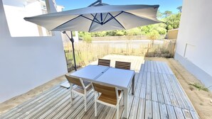 Eine Terrasse mit Tisch, Stühlen und einem Sonnenschirm, außerdem eine Holzterrasse.