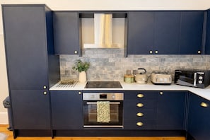 Une cuisine moderne avec des meubles de couleur sombre, une cuisinière en acier inoxydable, un four encastré et un four à micro-ondes.
