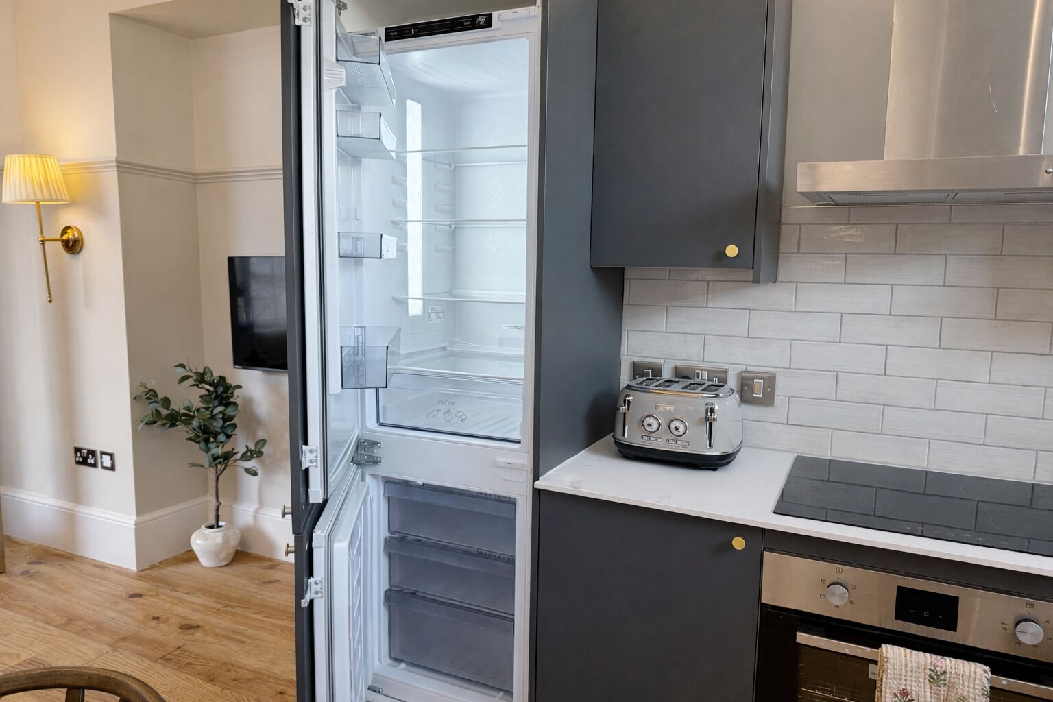 Una cocina moderna con refrigerador empotrado, tostadora y estufa.