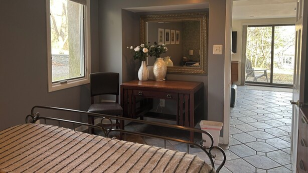 A bedroom with a bed, a chair, a dresser, a mirror, and a window.