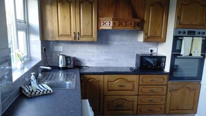Eine Küche mit Holzausstattung, einer schwarzen Arbeitsfläche, einem Wasserkocher, einem Toaster und einem Backofen.