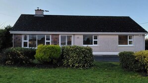 Ein eingeschossiges Haus mit Ziegeldach, weißen Fensterrahmen und einem Schornstein.