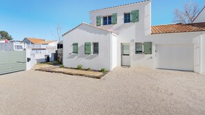 Un edificio blanco de dos pisos con camino de entrada de grava y una puerta verde.