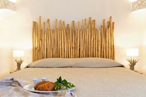 Ein Bett mit Holz-Kopfteil, ein Nachttisch mit Lampe sowie ein Tablett mit Speisen und Getränken auf dem Bett.