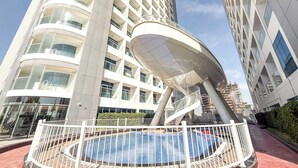 Un edificio moderno con una piscina circular, un espacio exterior cubierto y una escalera de caracol.