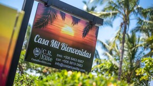 En skylt med texten ”Casa Mi Bienvenidas” och kontaktuppgifter till C.R. Elite i Costa Rica.