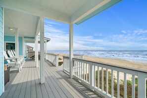 Une terrasse en bois avec des balustrades blanches donnant sur une plage.