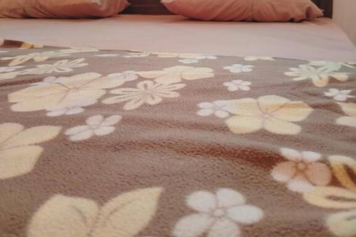 A bed with a floral-patterned blanket, a wooden headboard, and two pillows.