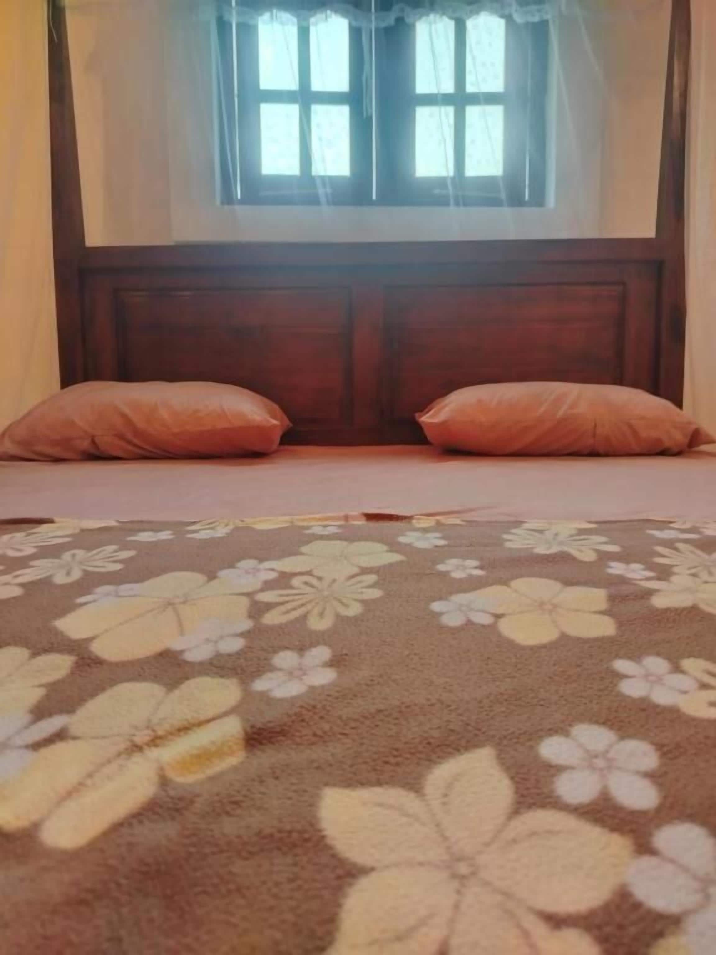 Un dormitorio con una colcha de estampado floral, cabecera de madera y dos almohadas a juego.