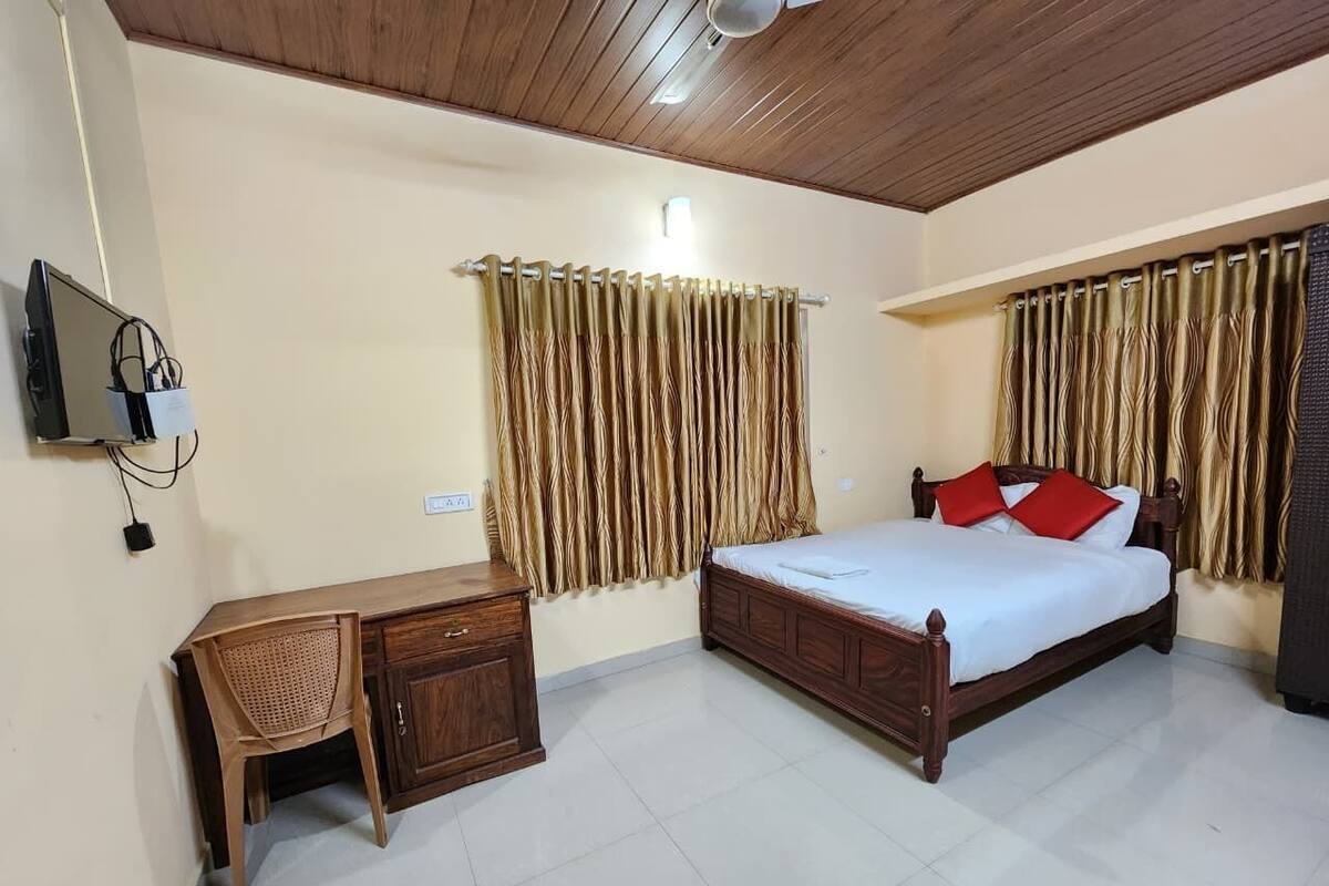 A bedroom with a wooden bed, a desk, and curtains.