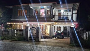 Ein zweistöckiges Haus mit befahrbarer Einfahrt, einem geparkten Auto und einer gut beleuchteten Fassade.