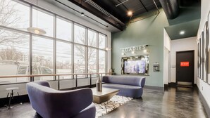 A modern lobby with large windows, a reception desk, and a seating area with sofas. - Downtown Condo · Walk to Broadway · Free Parking (Nashville)