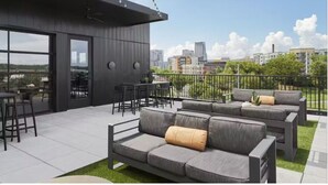 A modern outdoor seating area with a sofa and chairs, a dining table, and a view of the cityscape. - Downtown Condo · Walk to Broadway · Free Parking (Nashville)