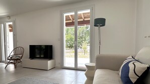 Una sala de estar con televisor, sofá, sillón y lámpara.