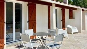 Un patio con una mesa, sillas, una puerta corrediza de vidrio y una chimenea.