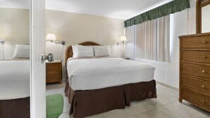 Una habitación de hotel con una cama grande, un aparador y un espejo.