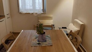 A dining area with a wooden table, four chairs, a potted plant, and a window with sheer curtains. - Stay in the heart of Tropea - the sea is just a 5-minute walk away (Tropea)