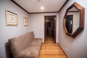 Ein Flur mit einem beigen Sofa, Holzboden und zwei gerahmten Bildern an der Wand.