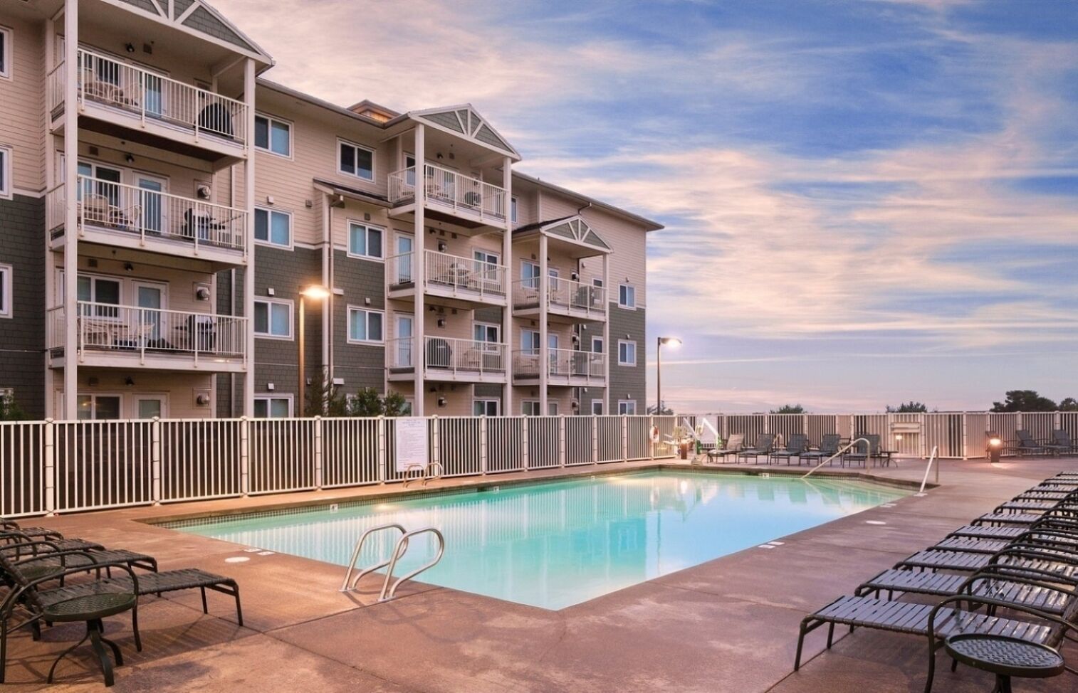 A multi-story hotel with a swimming pool, outdoor seating, and balconies.