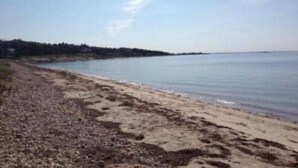 A beach with a pebbly shore and calm water. - Expansive Family Home with Water Views (Marion)