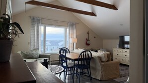 A cozy living room with a dining area, a sofa, a TV, and a guitar. - Expansive Family Home with Water Views (Marion)
